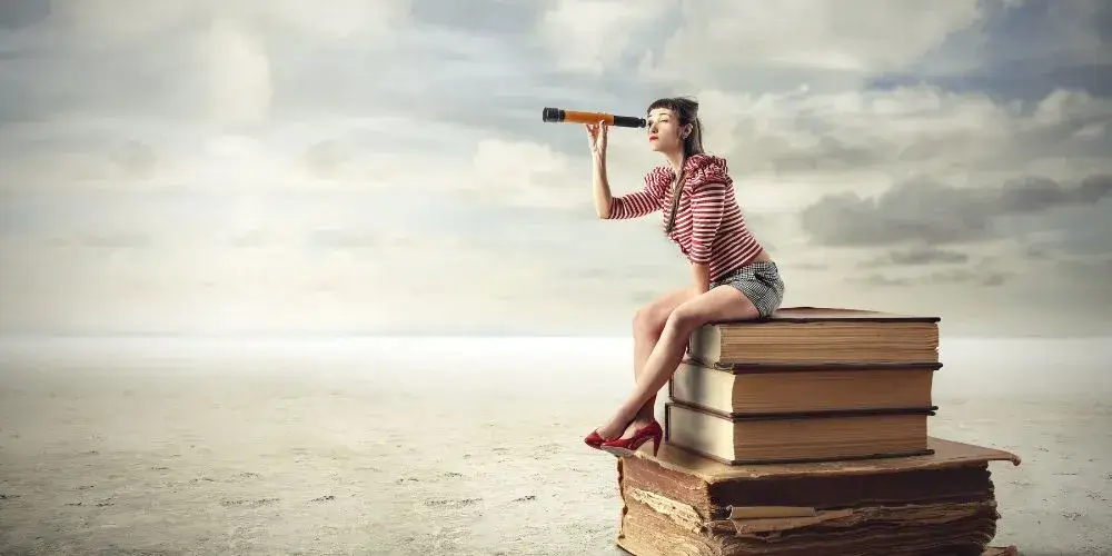 本の上に乗る女性が望遠鏡のようなもので遠くを見ている